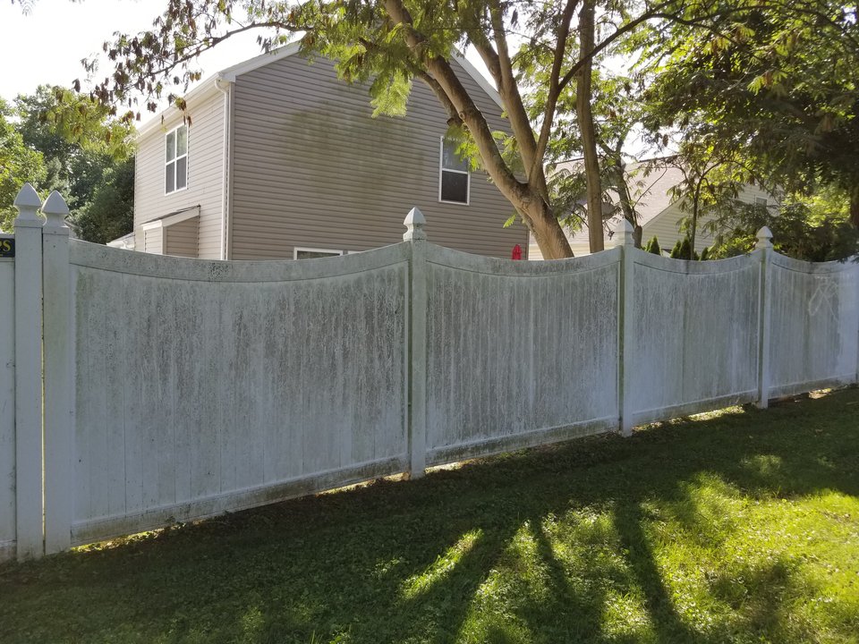 Vinyl privacy fence panels covered in heavy green algae growth before cleaning in Morrow, Ohio